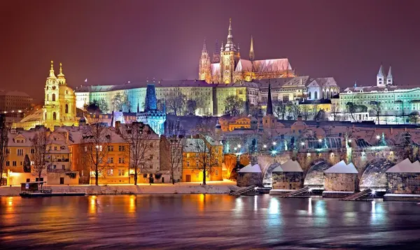 Noční panorama Prahy s osvětlenými památkami a odrazy na vodě